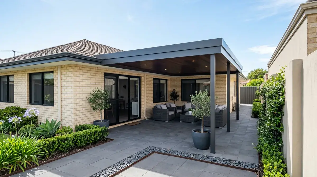 Low flat Colorbond patio roof over a paved courtyard behind a 1960s Cloverdale brick home, boundary wall tight on one side and a driveway on the other