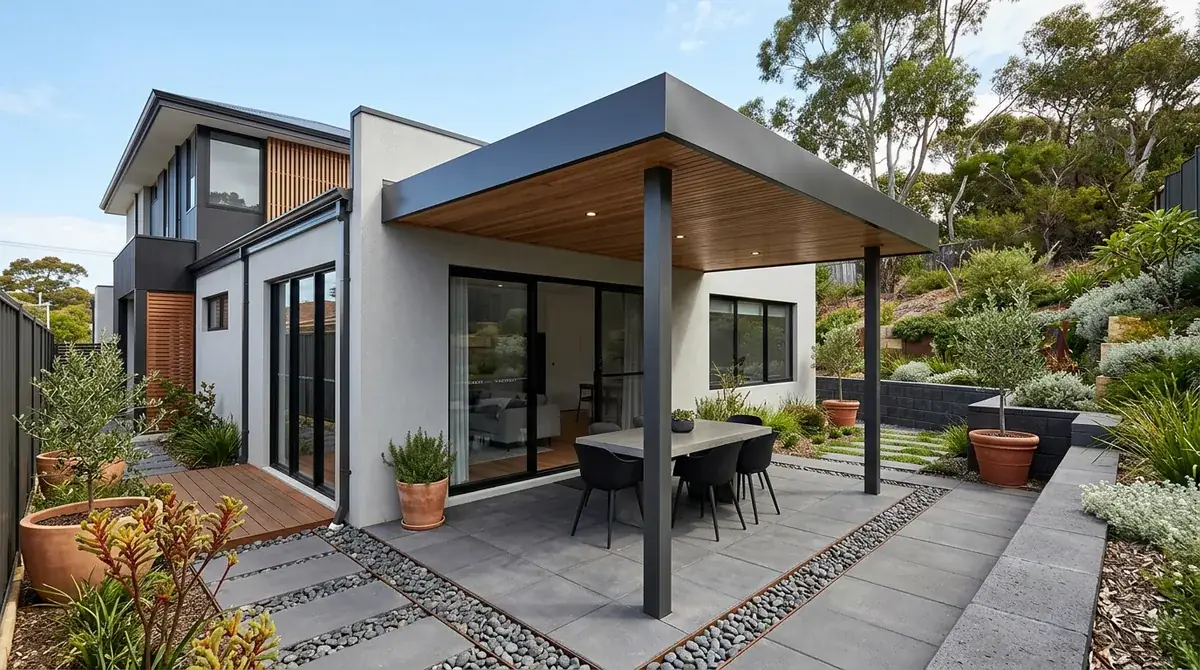 Flat Colorbond patio roof over a narrow rear courtyard on a split infill lot in Midland, with the ground rising toward Greenmount behind the fence