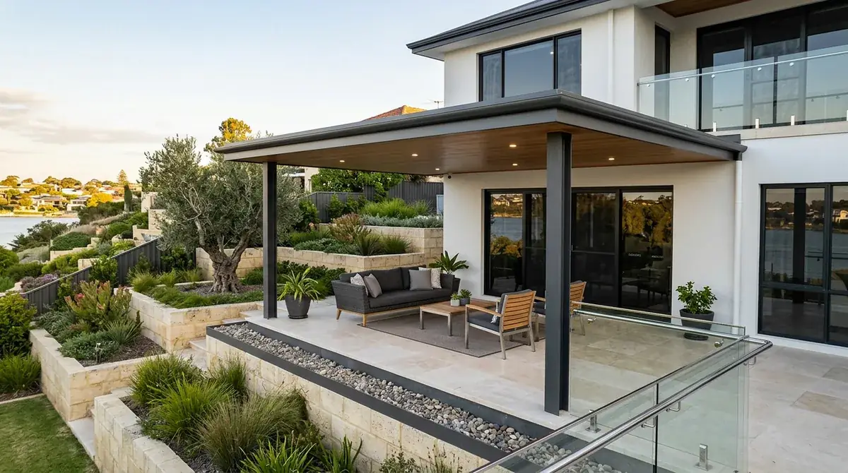 A flat patio roof holding a level plane over a terraced Mosman Park back yard, limestone block retaining stepping down the slope beneath it