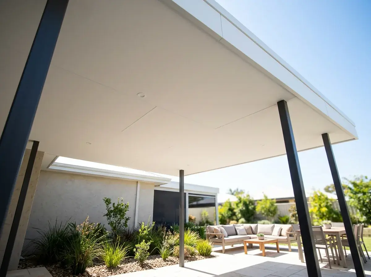 The underside of a wide insulated panel flat patio, one unbroken white ceiling running out to the fascia with the sunlit garden beyond